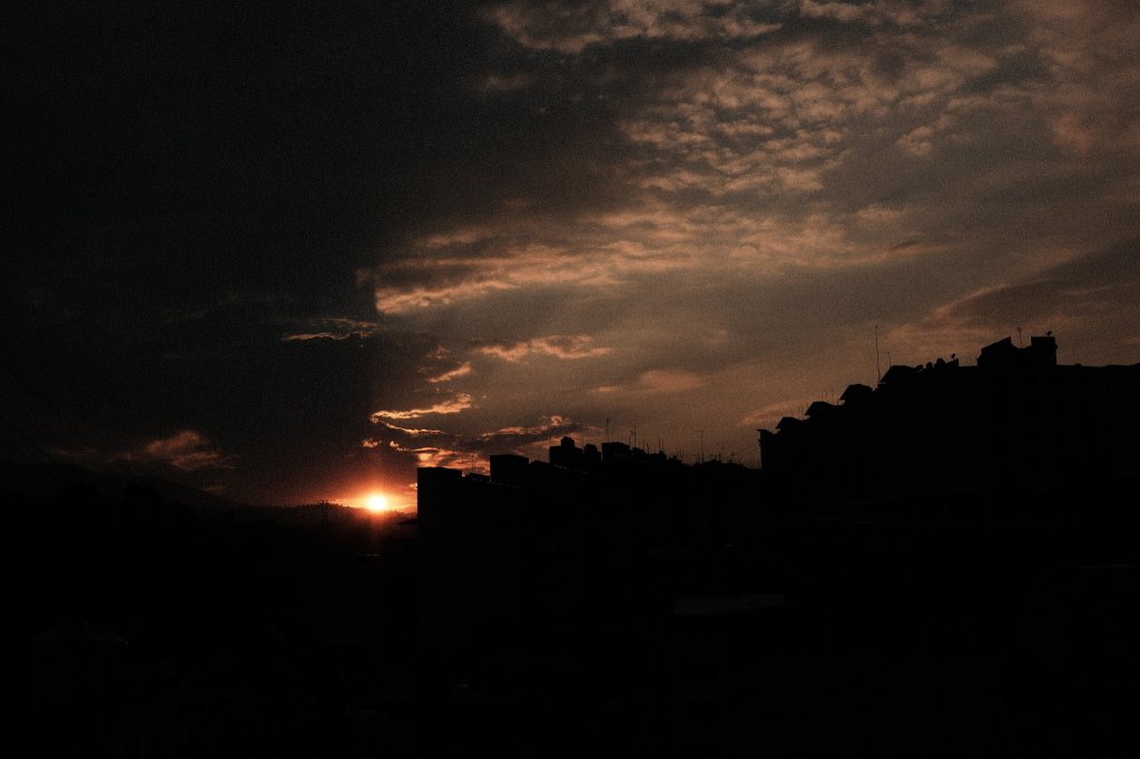 Atardecer urbano con cielo parcialmente nublado y siluetas de edificios, captado desde una azotea