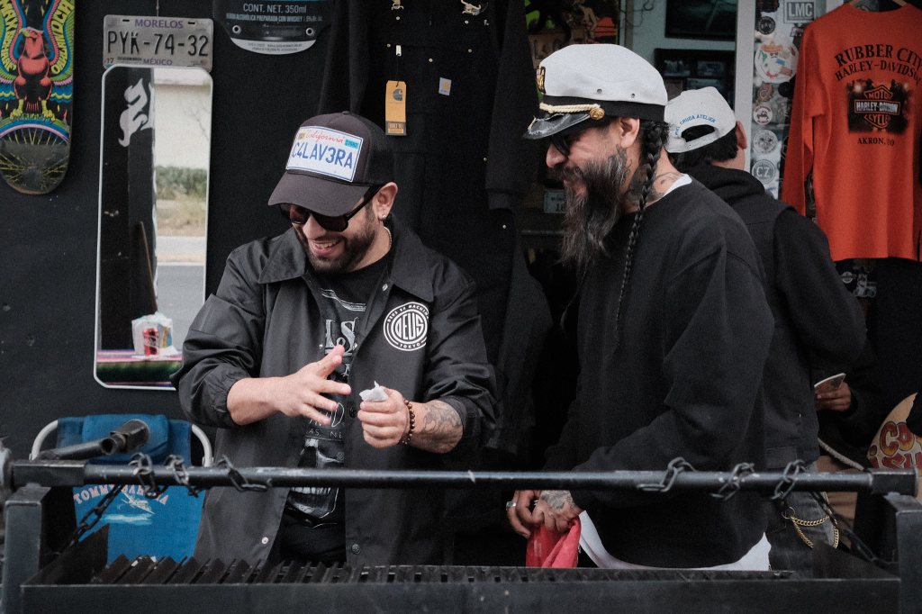 Motociclistas sonriendo mientras encienden una parrilla para carne asada
