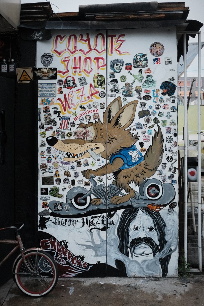 Pared de madera con stickers con una pintura de un coyote en patineta