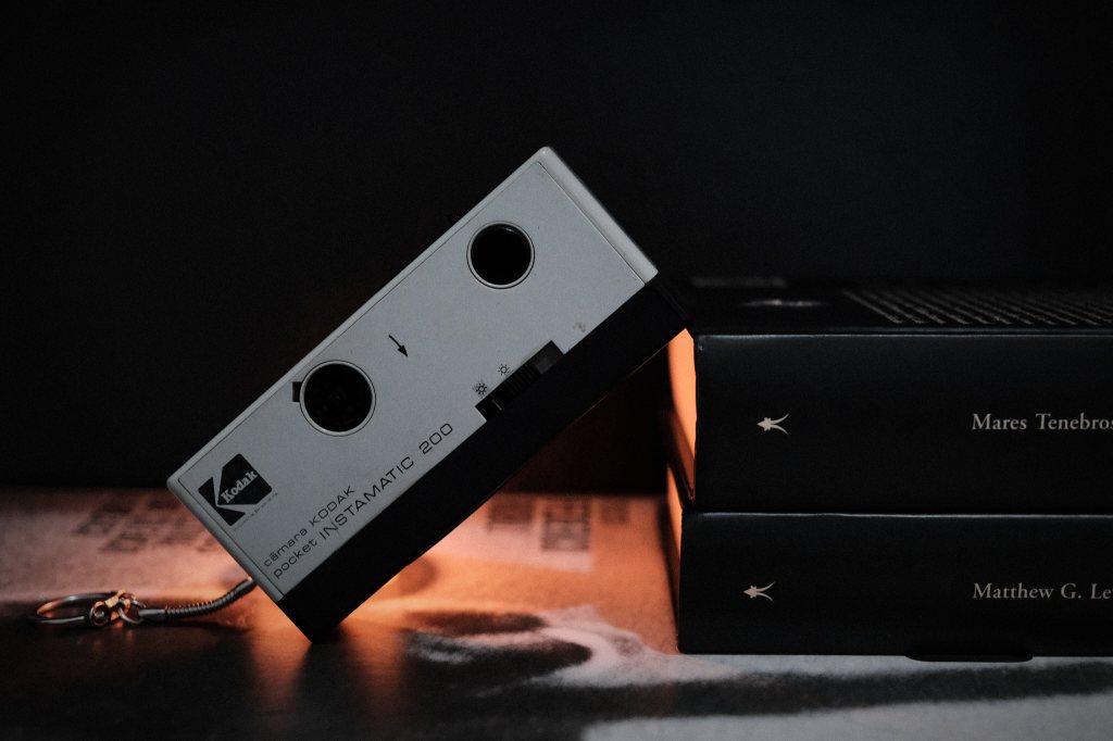 Cámara Kodak Pocket Instamatic 200 con luz cálida y libros